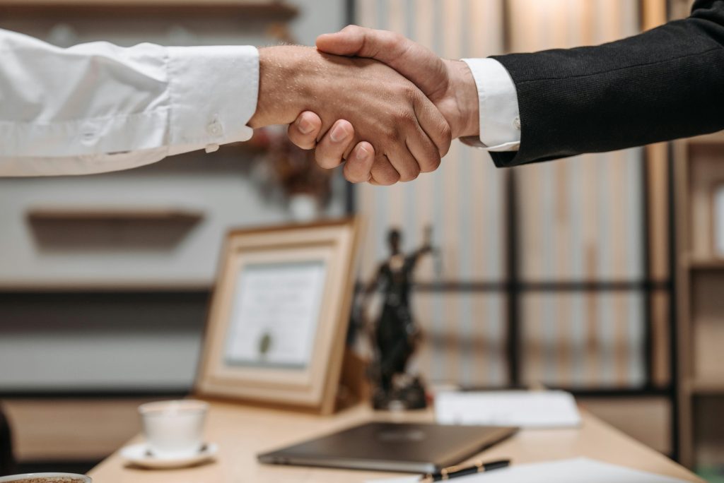 Despacho Moreno Infante Madrid - Close-up of a handshake between two professionals in a modern office setting, emphasizing partnership and agreement.